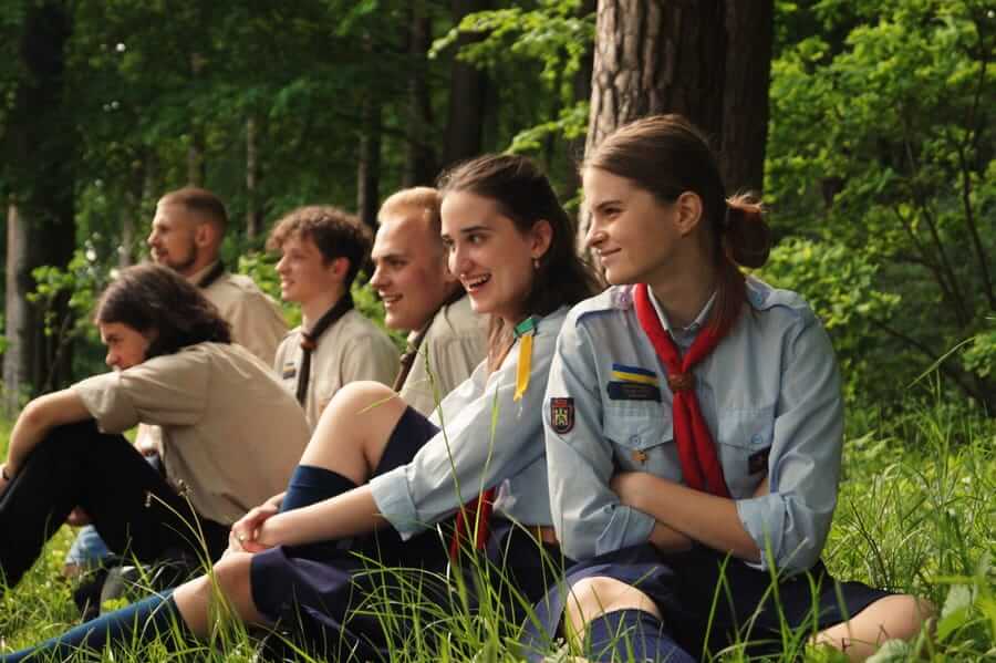 Мандрівники та мандрівниці сидять на траві в лісі